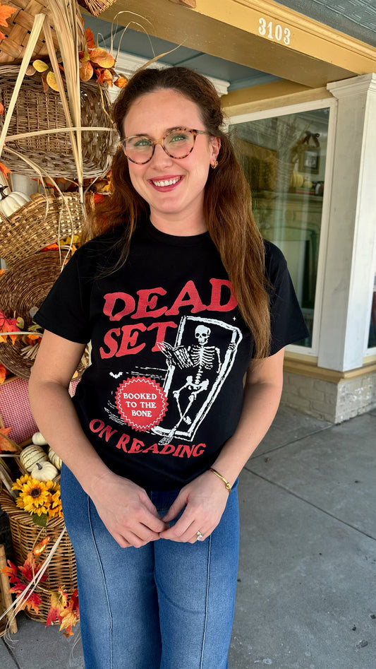 Person wearing a black t-shirt with red text and graphics, standing outdoors.