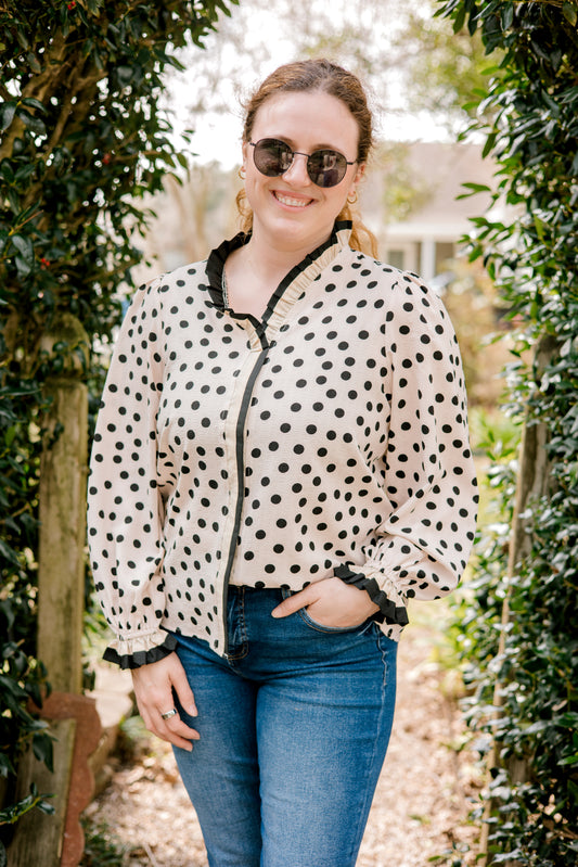 Woman wearing a polka dot blouse and sunglasses outdoors