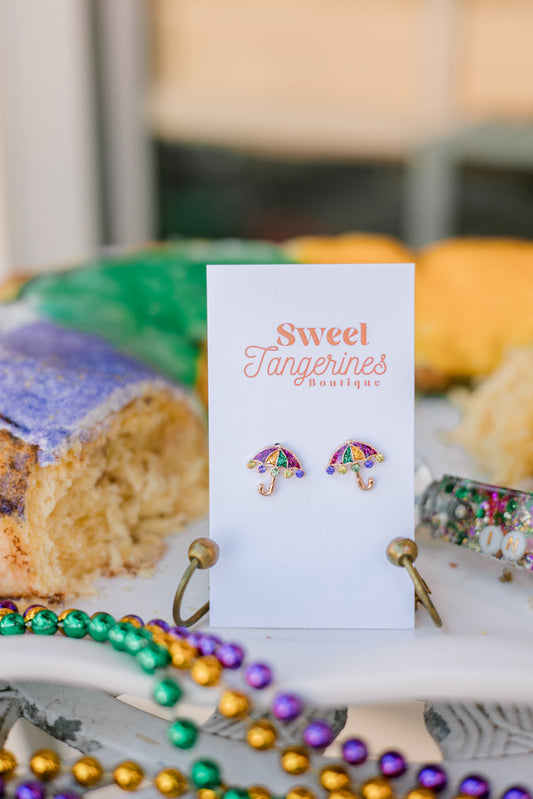 Earrings on a card with 'Sweet Tangerines' branding, surrounded by colorful beads and pastries.