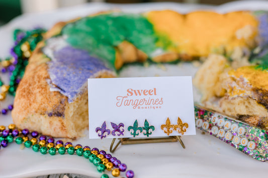 Decorative king cake with Mardi Gras beads and a sign for Sweet Tangerines Boutique.