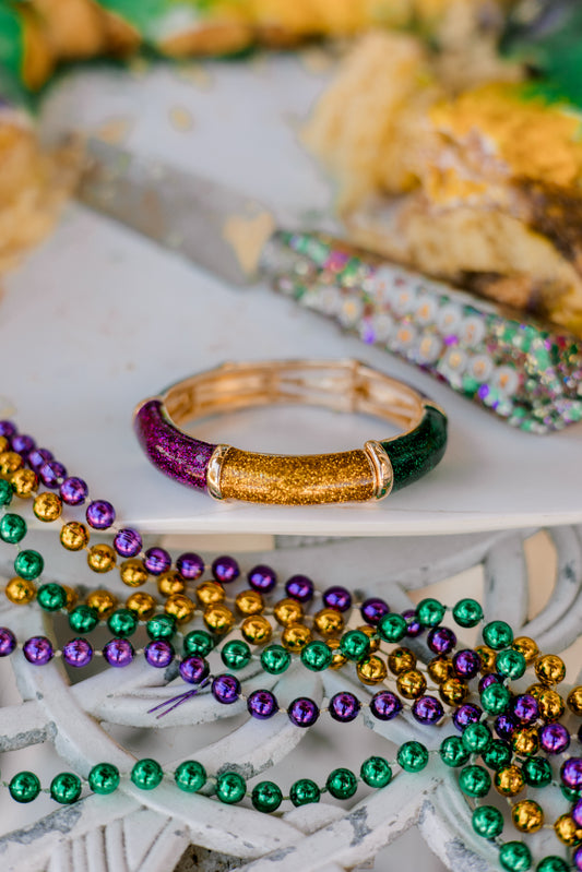 Colorful beads and a gold bracelet on a white surface with blurred festive background