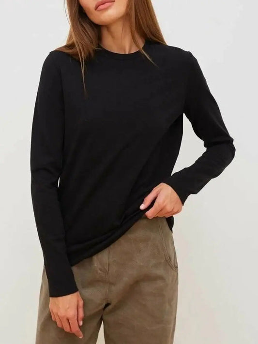 Person wearing a black long-sleeve top and brown pants against a white background