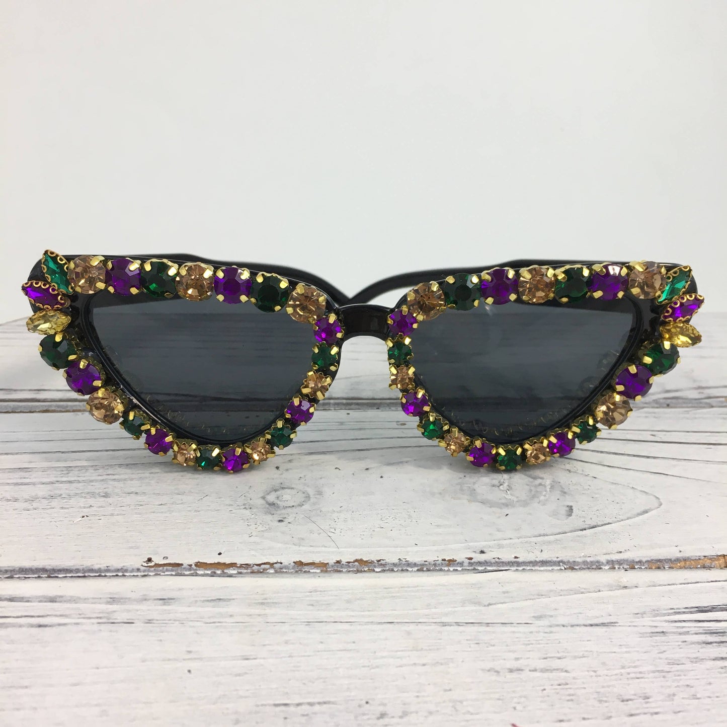 Sunglasses with colorful gemstones on a white wooden surface