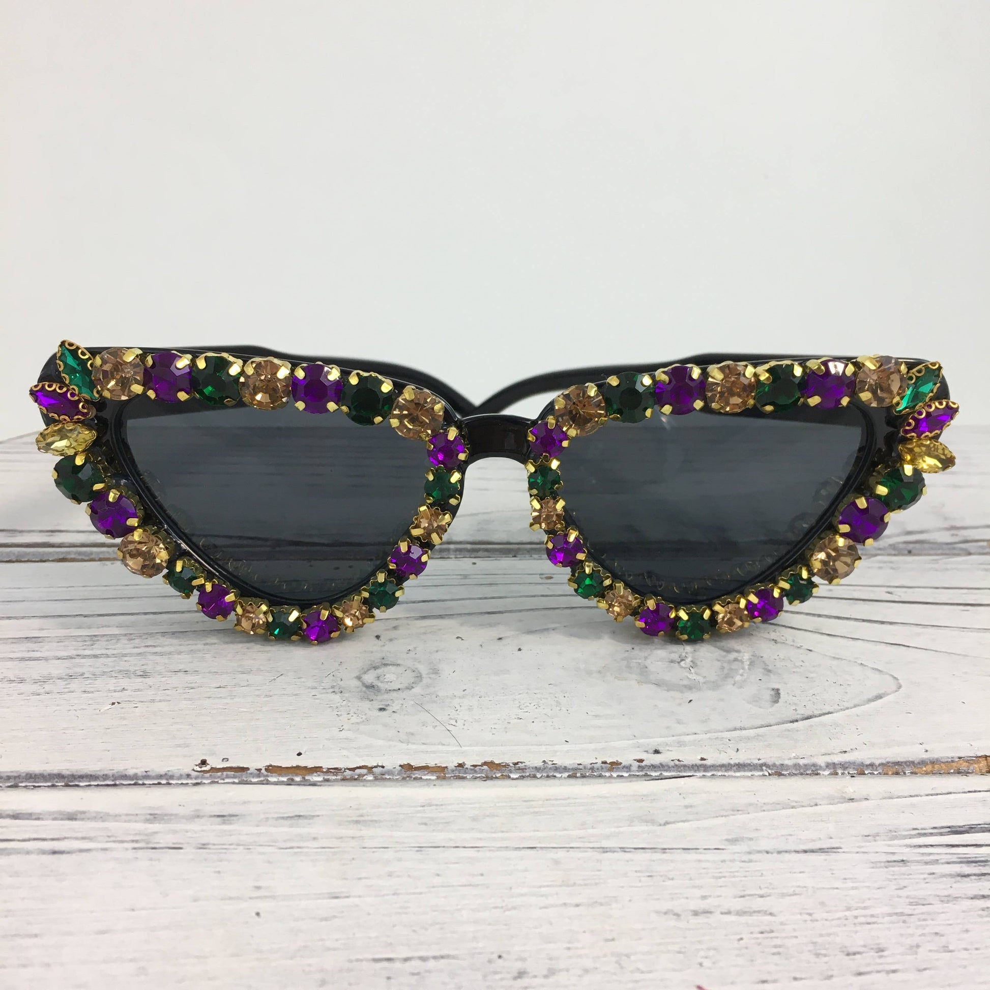 Sunglasses with colorful gemstones on a white wooden surface