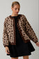Woman wearing a leopard print cardigan over a black dress on a gray background
