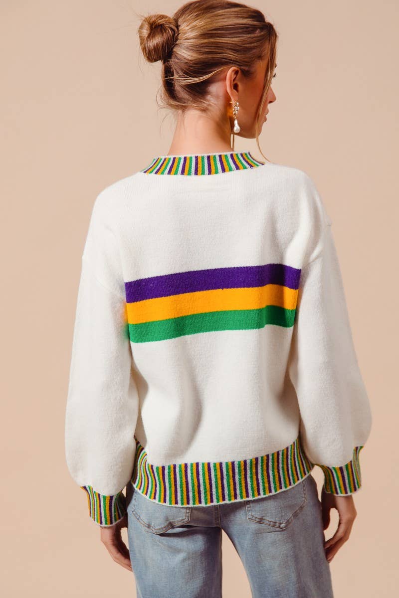 Person wearing a white sweater with colorful stripes on a beige background