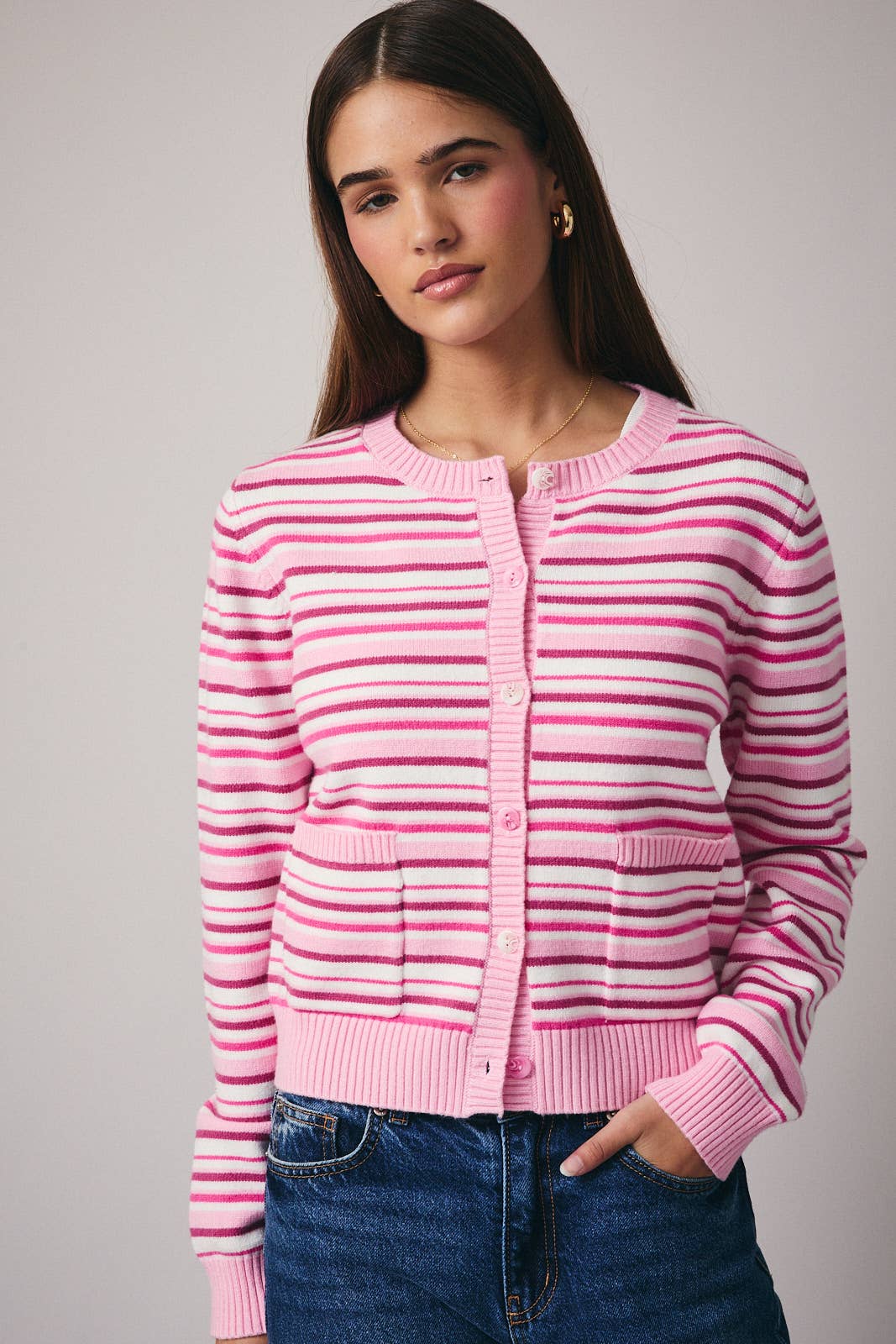 Woman wearing a pink striped cardigan against a gray background