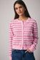 Woman wearing a pink striped cardigan against a gray background