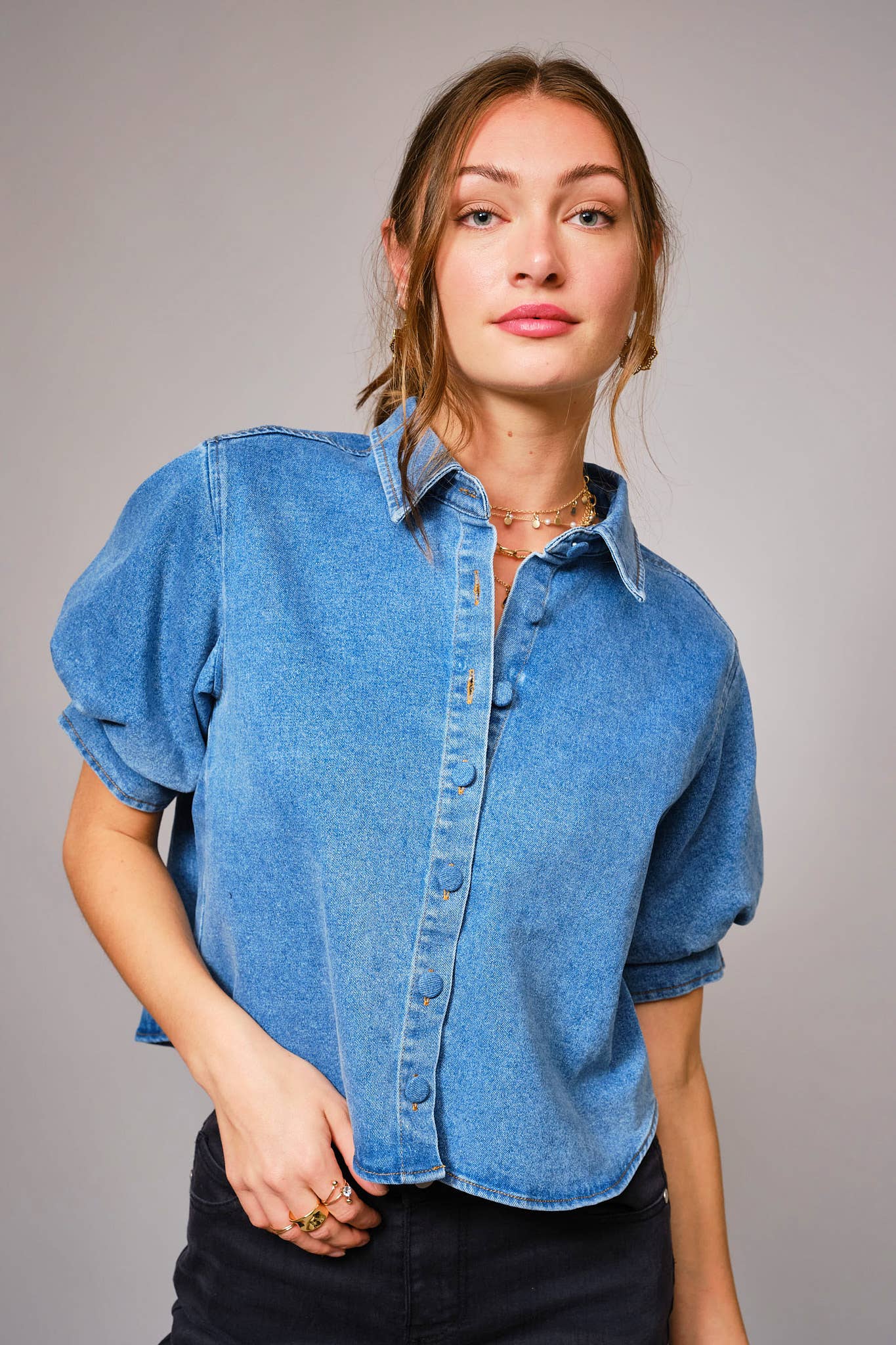 Woman wearing a blue denim shirt against a gray background