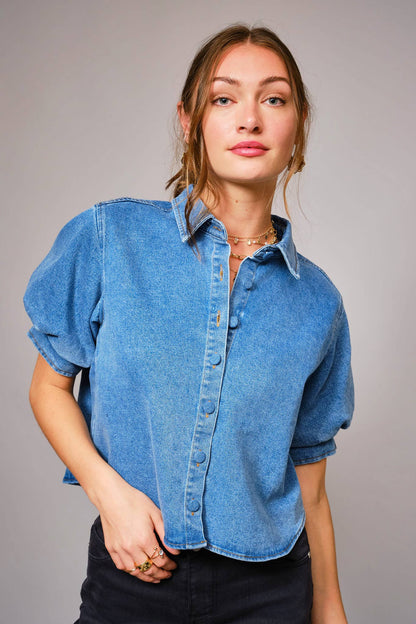 Woman wearing a blue denim shirt against a gray background