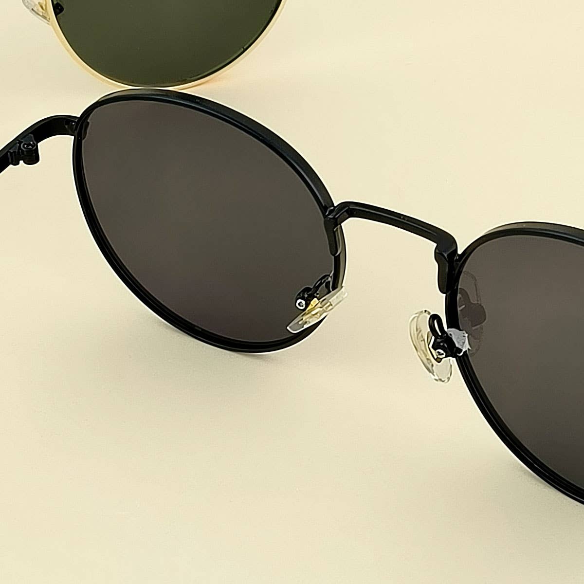 Round sunglasses with black frames and dark lenses on a beige background