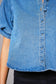Close-up of a blue denim shirt with buttons on a gray background