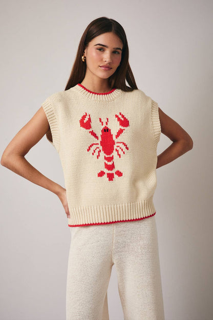 Woman wearing a cream sleeveless sweater with a red lobster design on a plain background