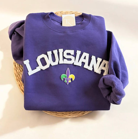 Purple sweatshirt with 'LOUISIANA' and a fleur de lis on a woven basket