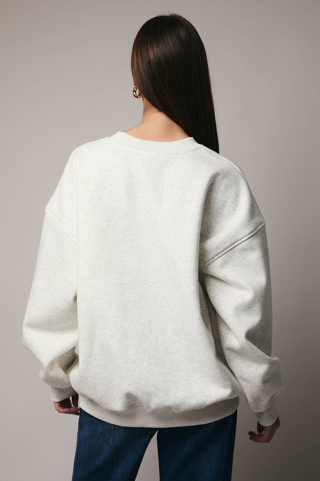 Person wearing a light gray sweatshirt with a neutral background