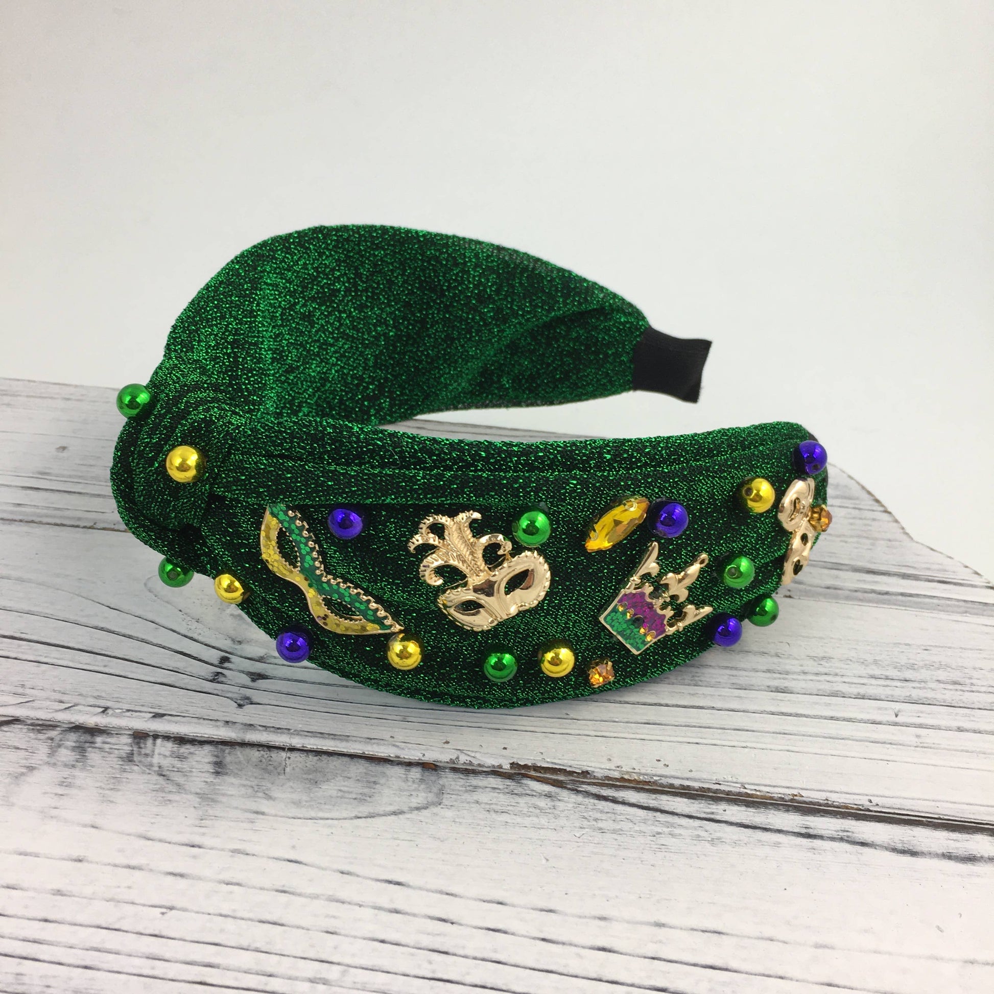 Green glittery headband with decorative pins on a wooden surface