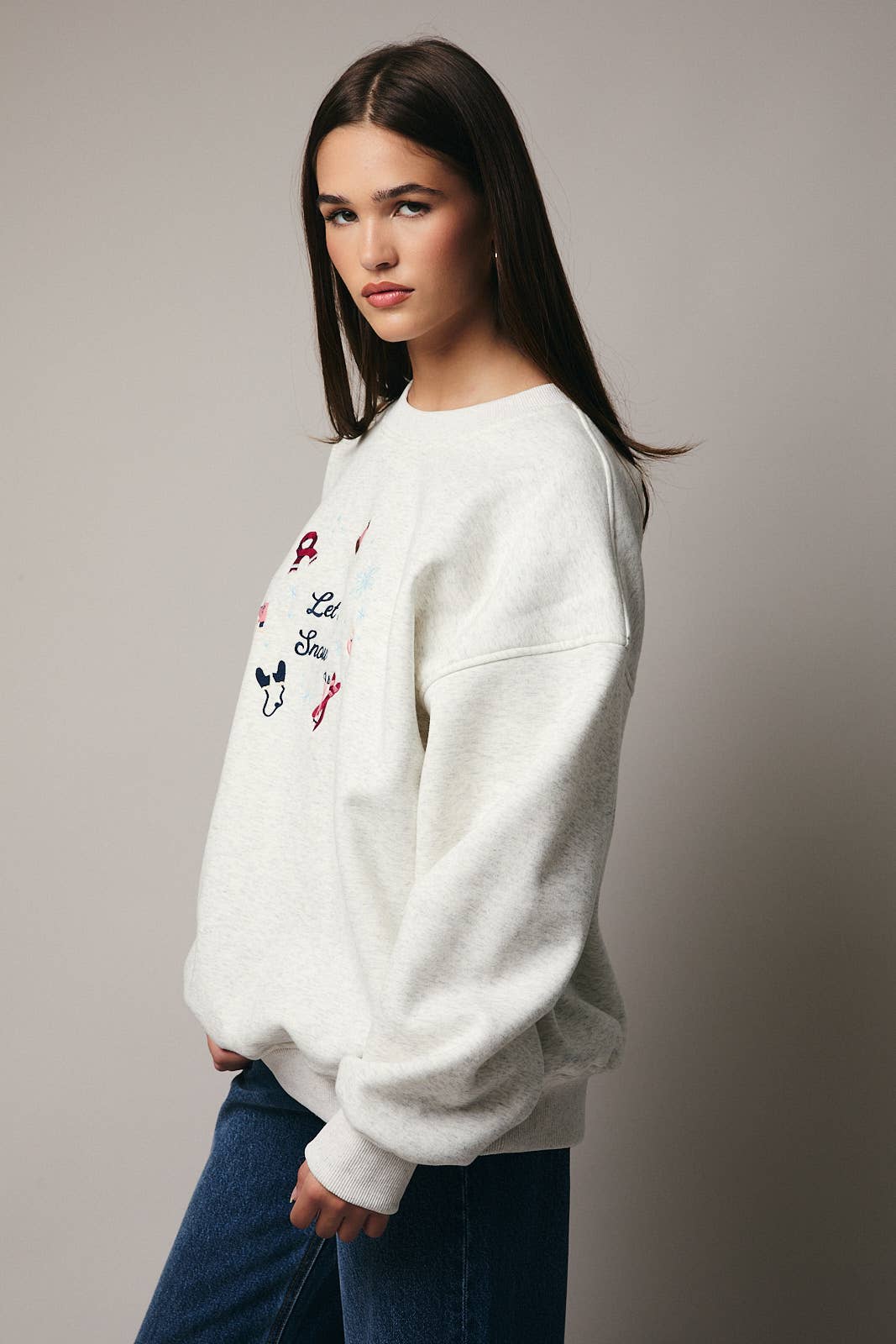 Woman wearing a white sweatshirt with text and graphics on a plain background