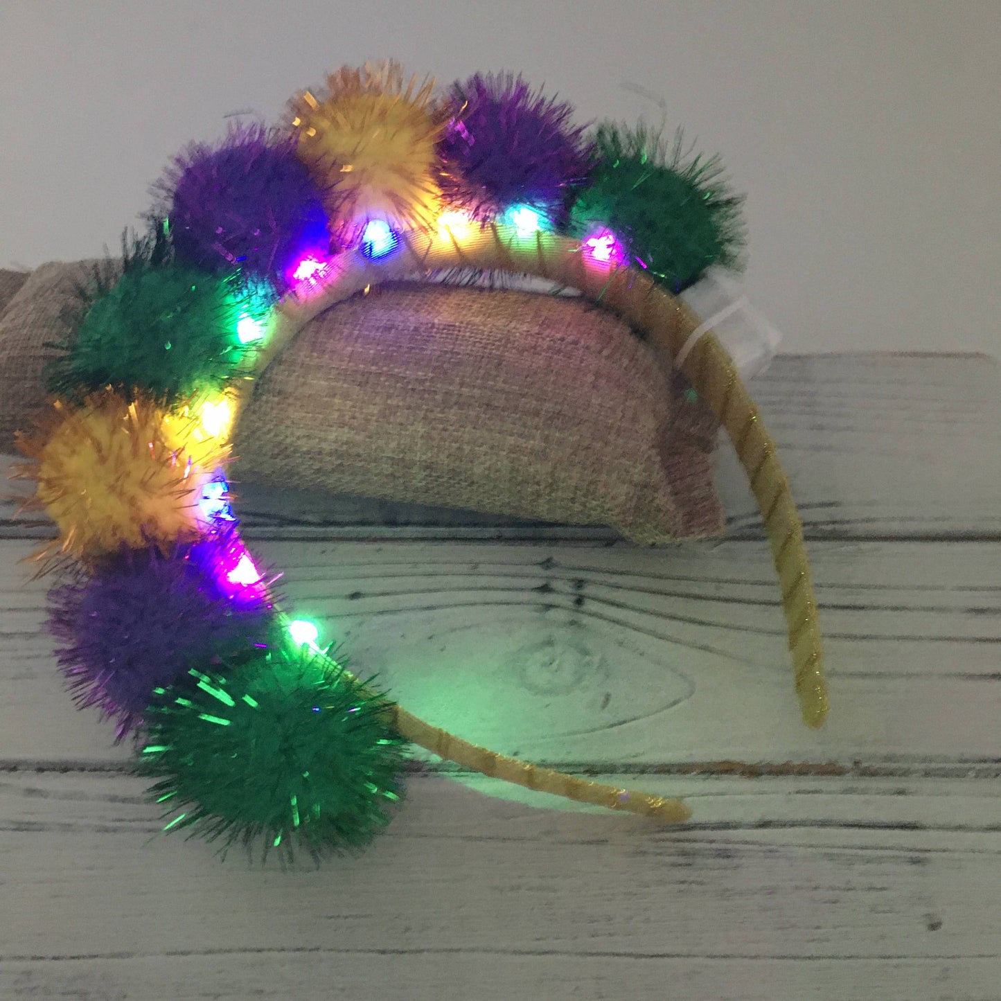 Colorful pom-pom headband with lights on a wooden surface