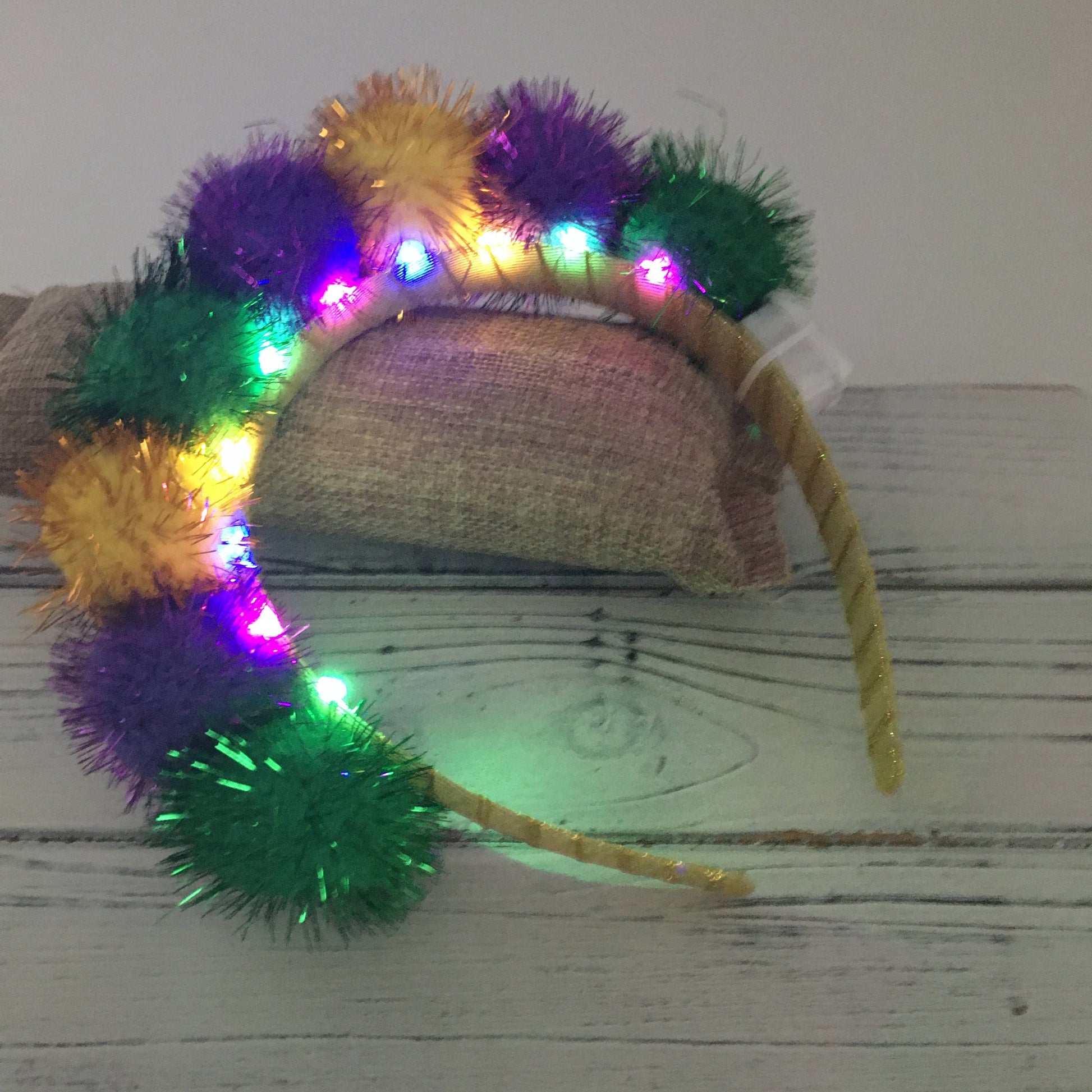 Colorful pom-pom headband with lights on a wooden surface