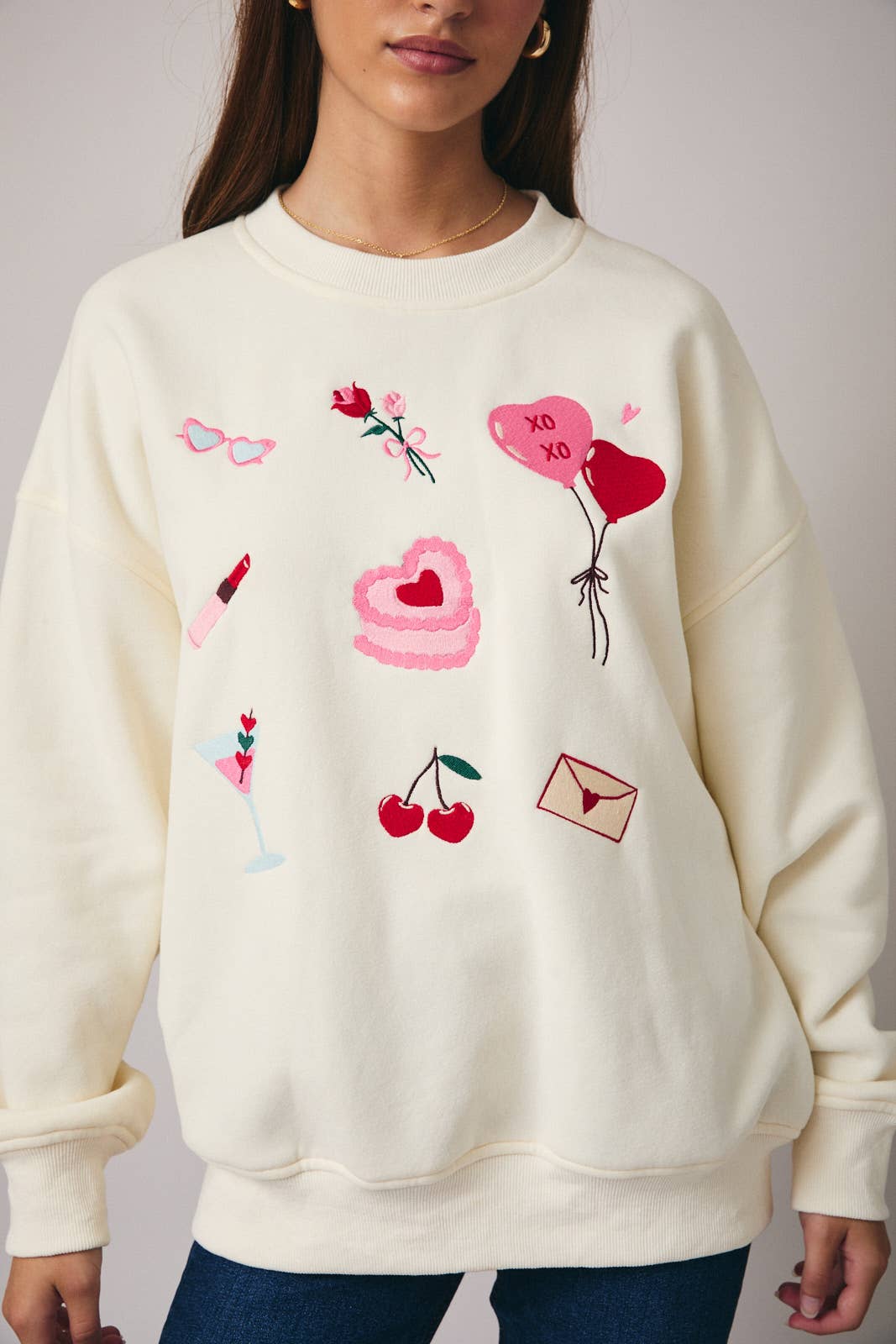White sweatshirt with colorful embroidered designs worn by a person