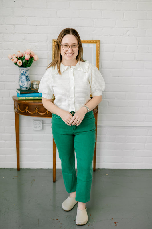 white ruffle cardigan/top with green jeans