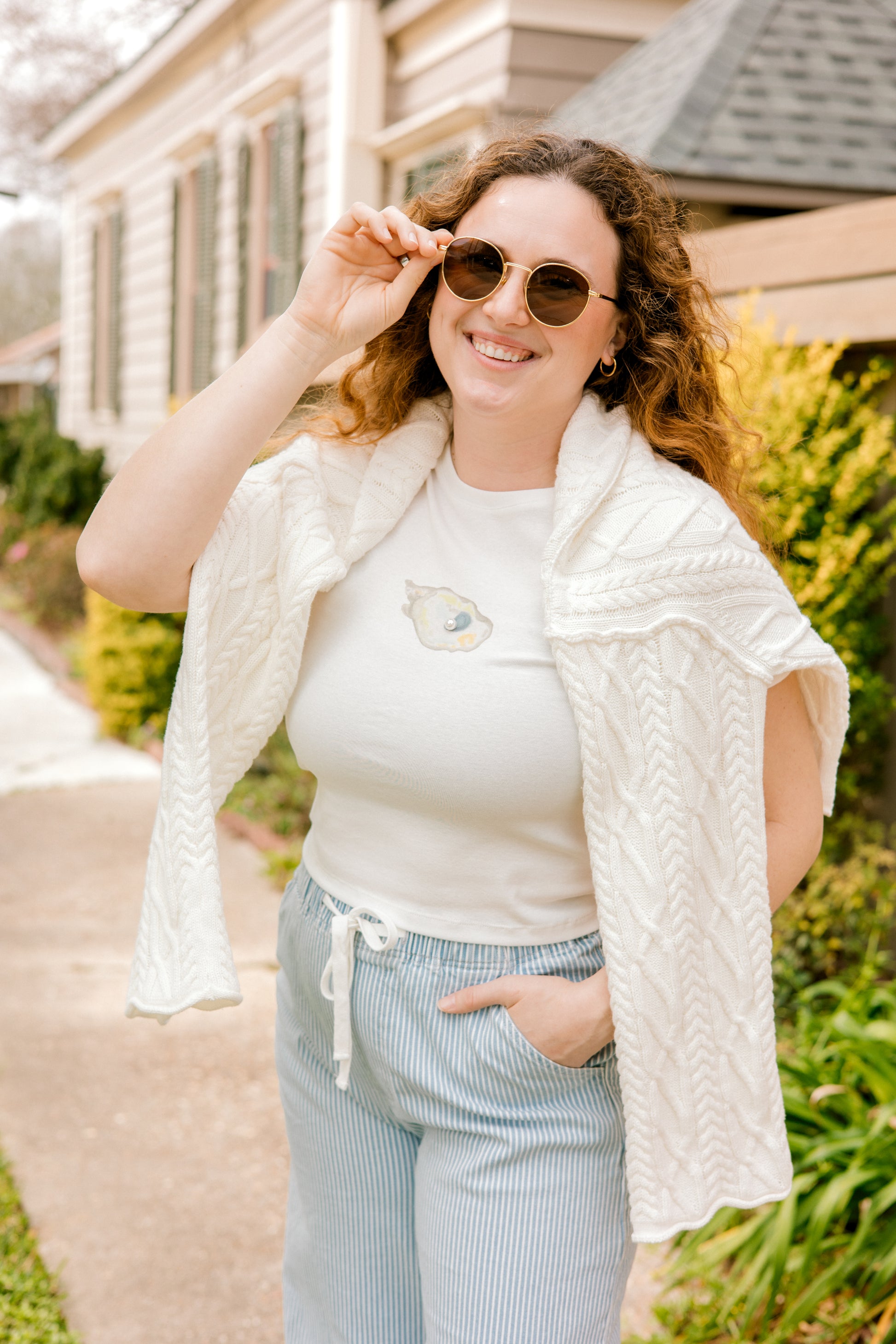 Woman wearing a white t-shirt with an oyster graphic design and pearl detail, 