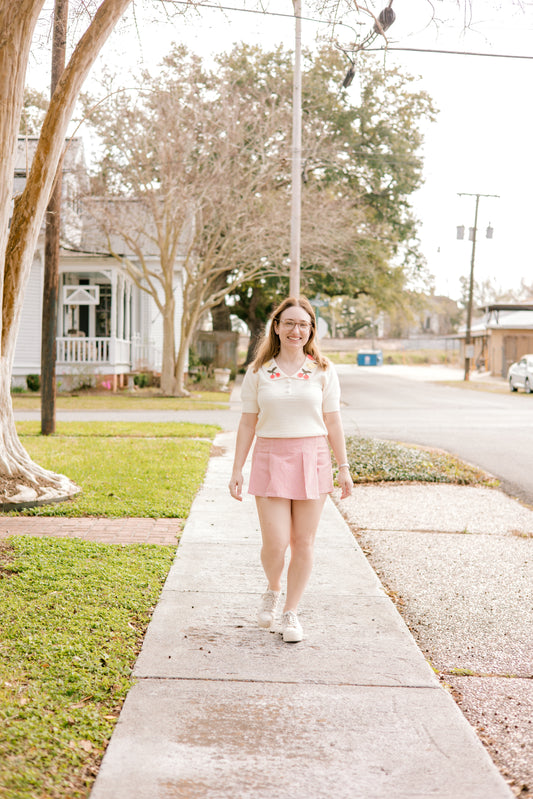 white sweater top with collar with fruit details and pink and white stripe skort
