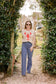 Woman walking through a garden wearing a sweater with a lobster design.