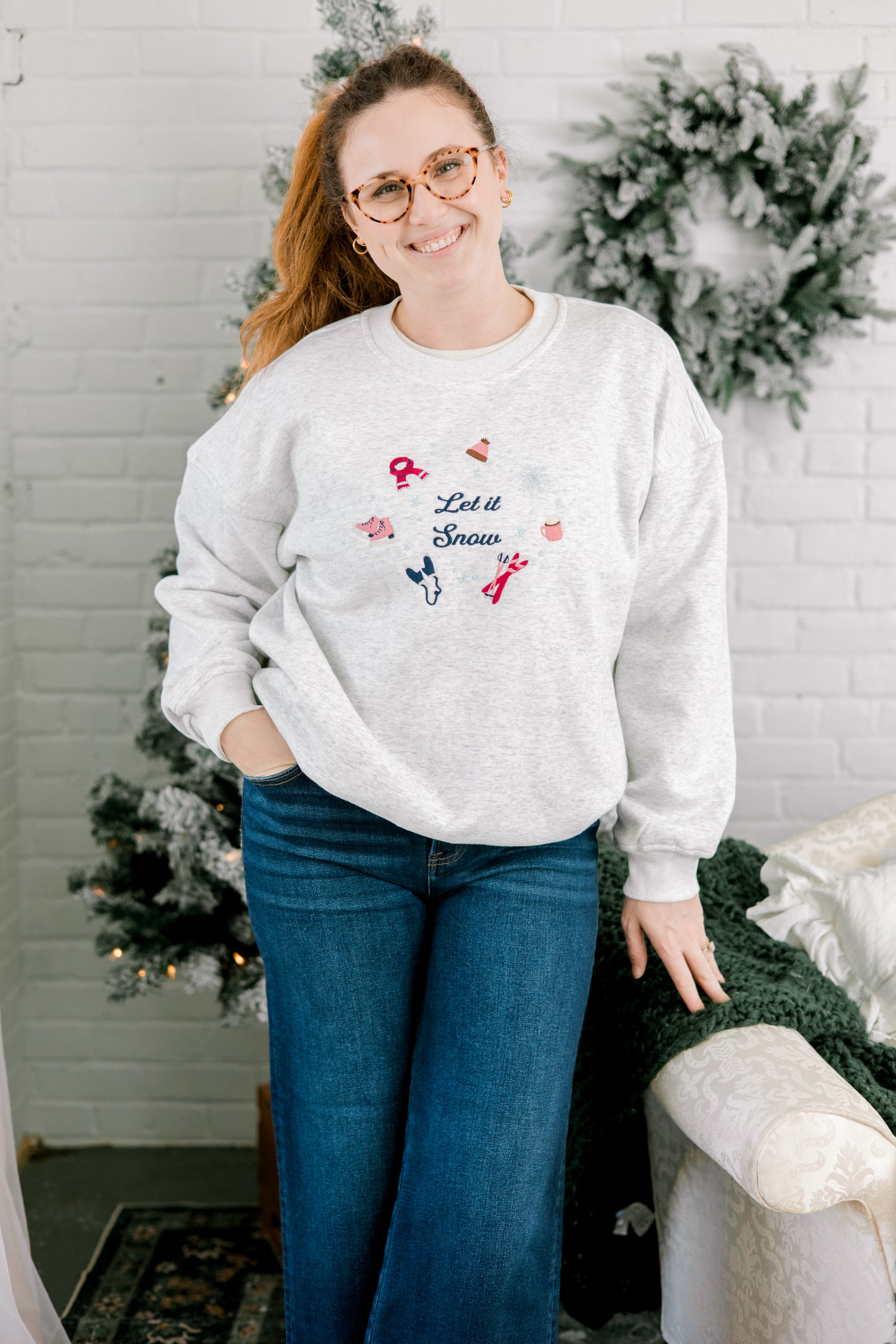 Person wearing a white sweatshirt with Christmas-themed design in a festive setting.