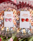 Heart-shaped earrings on cards with 'Sweet Tangerines Boutique' branding, surrounded by colorful heart-shaped candies.