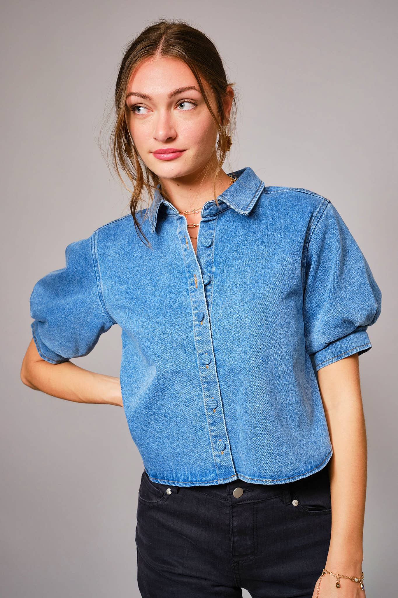 Woman wearing a blue denim shirt against a gray background