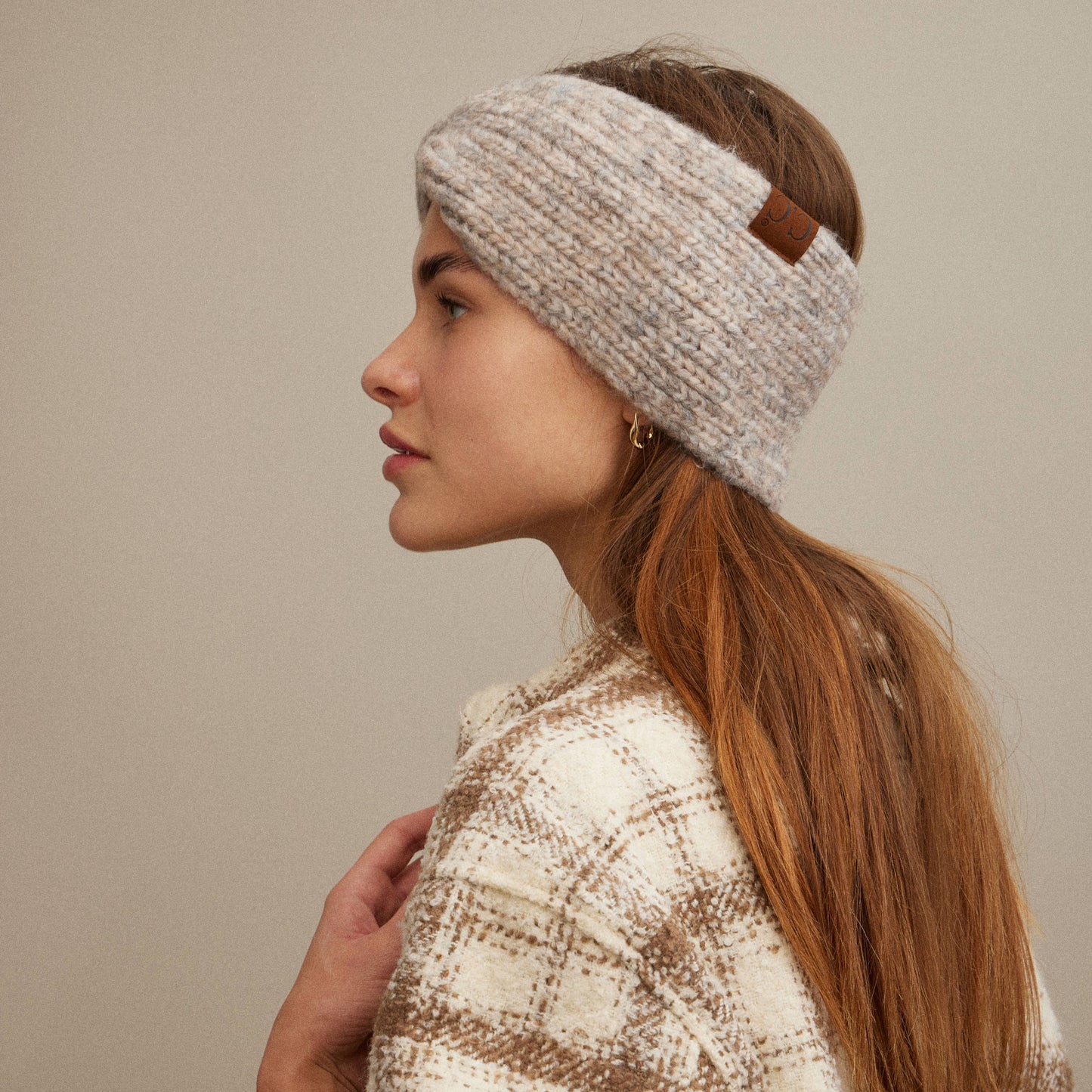 Woman wearing a knitted headband against a neutral background
