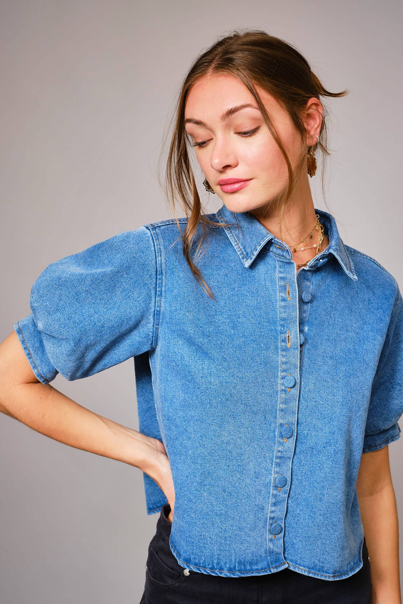 Woman wearing a blue denim shirt against a gray background