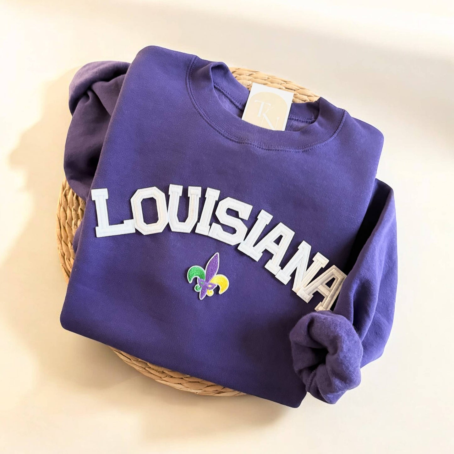 Purple sweatshirt with 'LOUISIANA' text and a logo on a light background