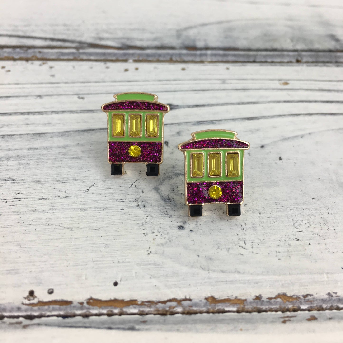 Colorful trolley-shaped earrings on a wooden surface